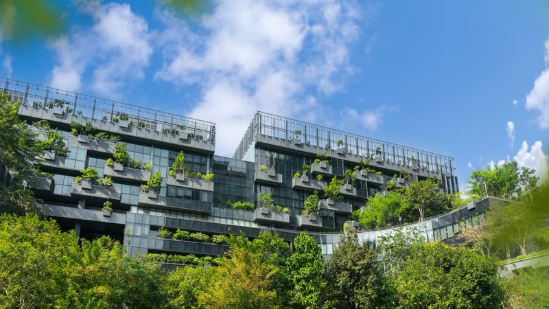 Eco-friendly building in modern city. Sustainable glass office building with trees for reducing CO2. Green architecture. Future green business concept. True Digital Park Bangkok Thailand