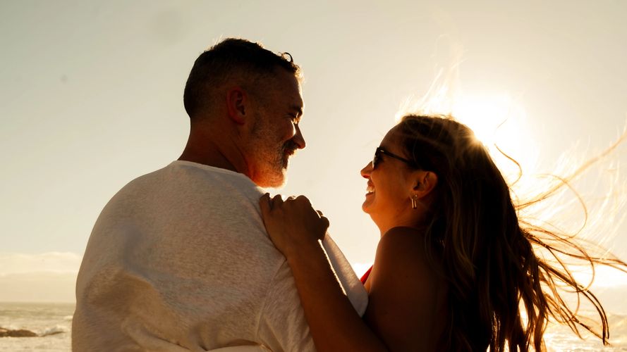 Couple sharing a joyful moment at sunset by the beach.