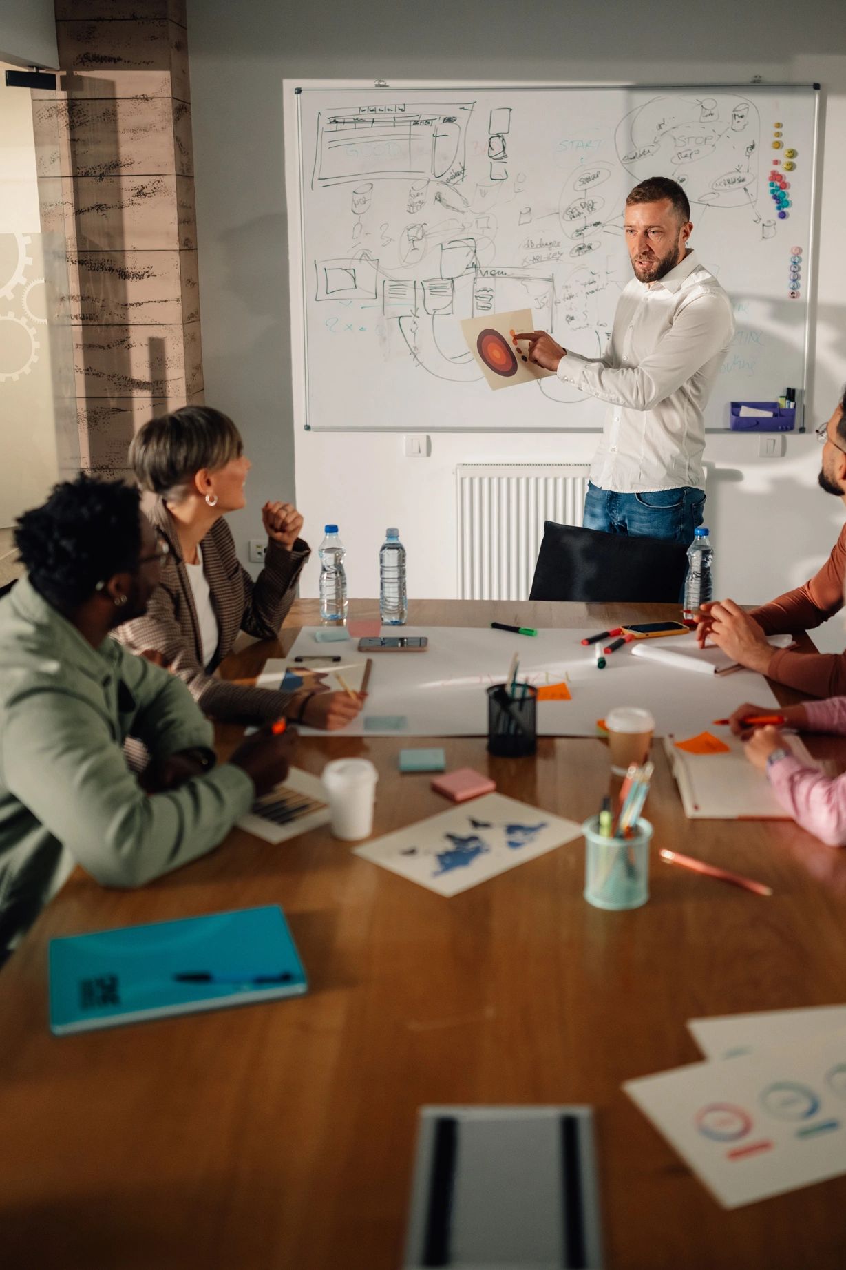 Man presenting a target chart to a group in a meeting room.