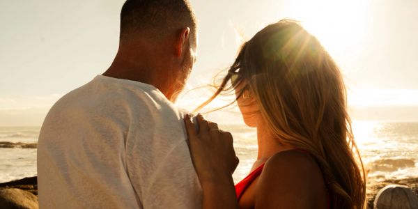 Couple embracing and watching the sunset by the sea.