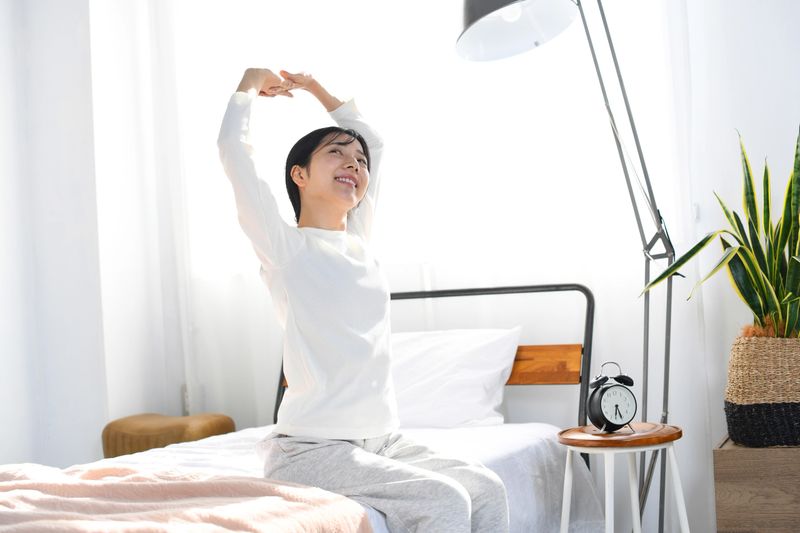 Asian young woman waking up in bed in the morning