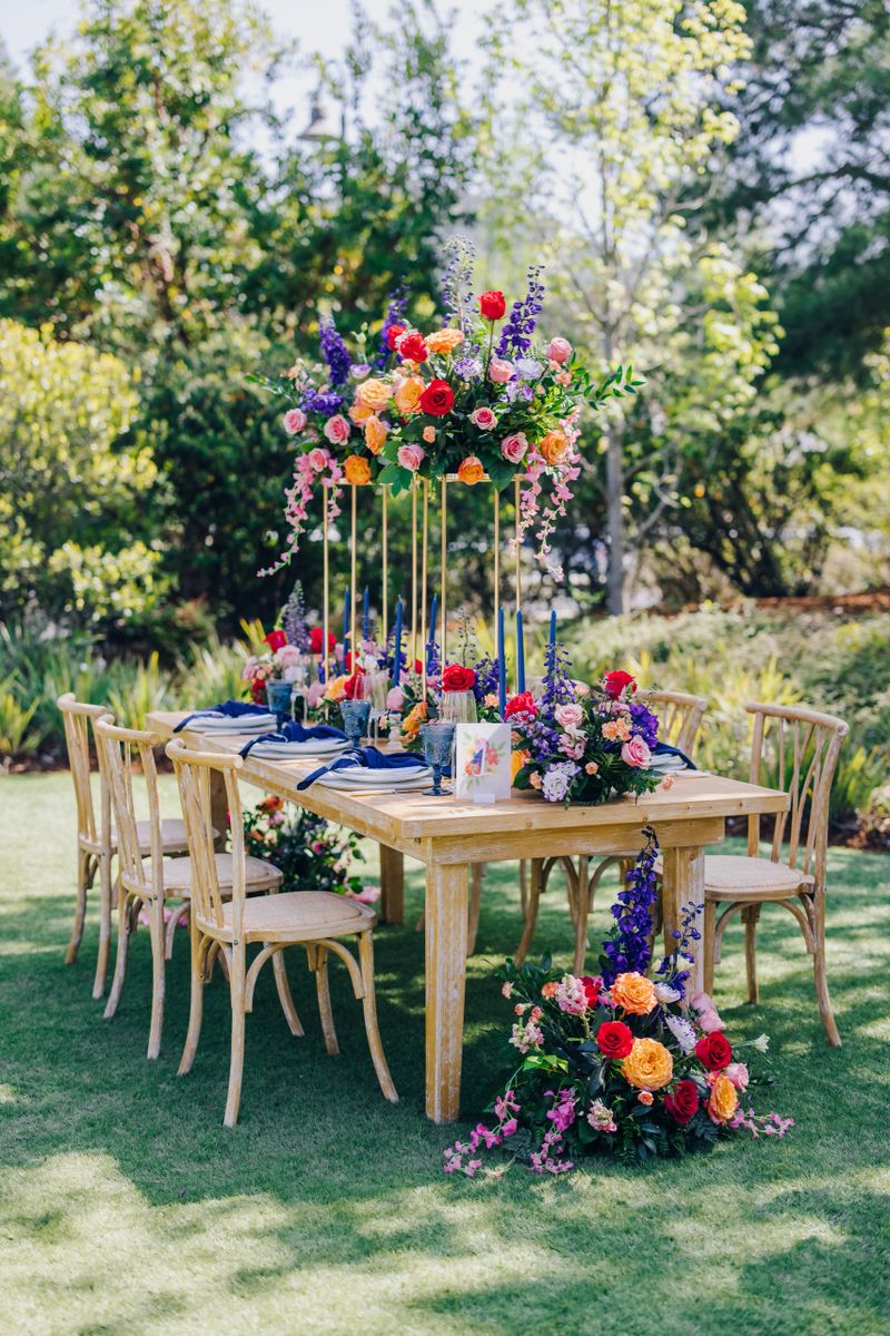 An exquisite outdoor dining table, beautifully adorned with vibrant and colorful floral decorations, paired with stylish seating, creating the perfect ambiance for memorable events and gatherings