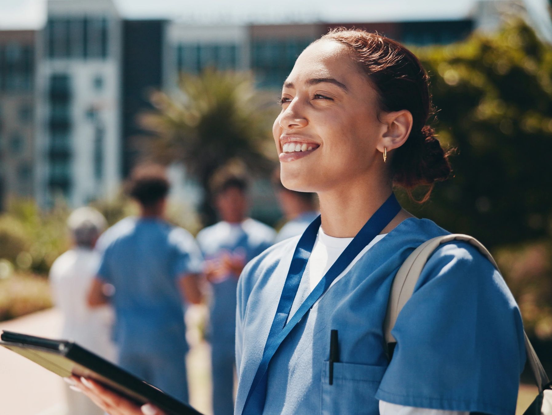 Smiling healthcare worker outdoors in scrubs.