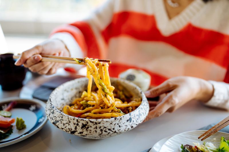 Close up of Asian daughter and her mother having lunch together in outdoor restaurant.