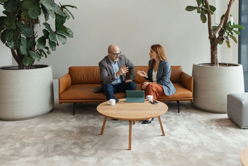 A casual yet focused conversation unfolds between two professionals, as they review information on a tablet, embodying a modern approach to teamwork and collaboration.