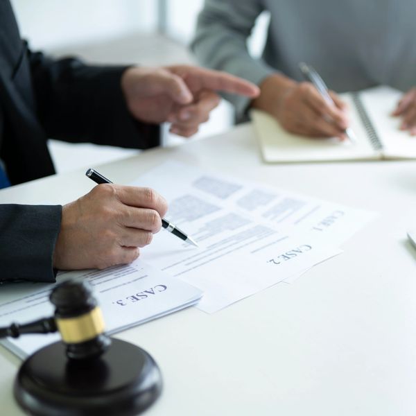 Two people discussing legal cases with documents and gavel on table.
