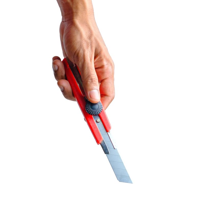 A close-up of a hand holding a cutter knife against a white background. The sharp blade and ergonomic grip emphasize precision and utility, making it ideal for concepts related to craftsmanship, DIY projects, and office supplies. Perfect for advertising, editorial content, and digital media.