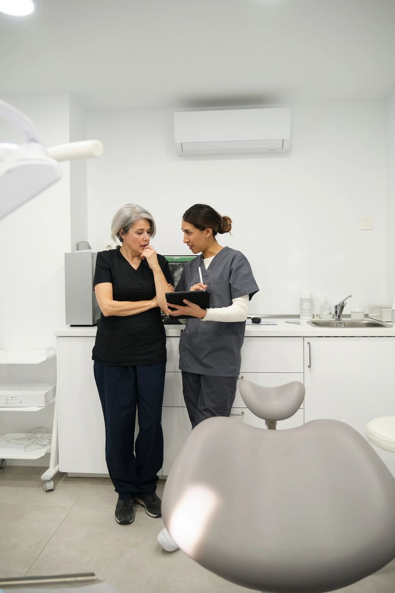 Two female dentists are discussing a radiography on a tablet in their modern dental clinic