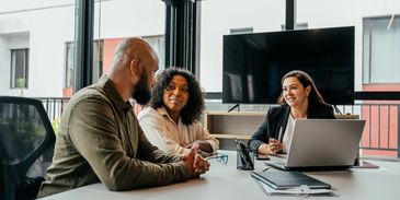 Three colleagues engaged in a meeting in a modern office.