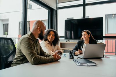 Three professionals engaged in a business meeting around a table.