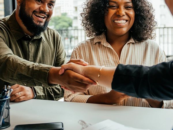 A professional woman discussing documents with a colleague in an office setting.