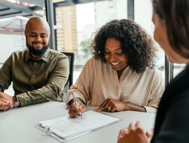 A woman filling a form inside an office while a man and another woman watch