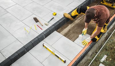 Worker installing outdoor tiles on a patio.