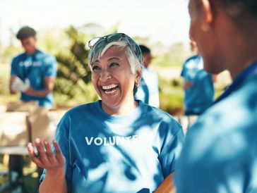Smiling volunteer in a blue shirt engaging with others outdoors.