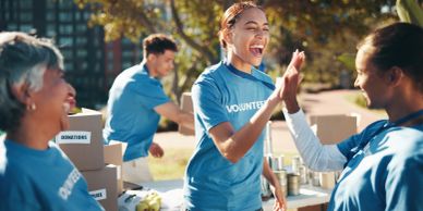 Volunteers high-fiving during outdoor charity event.