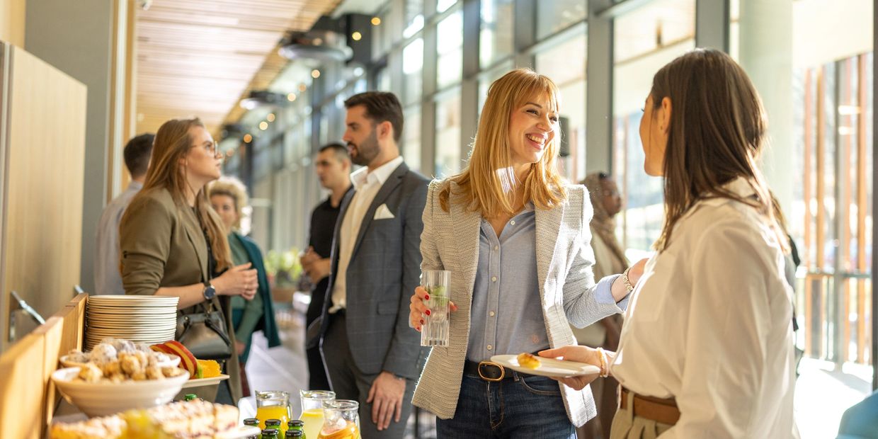 People engaging in conversation at a well-lit social gathering with food and drinks.