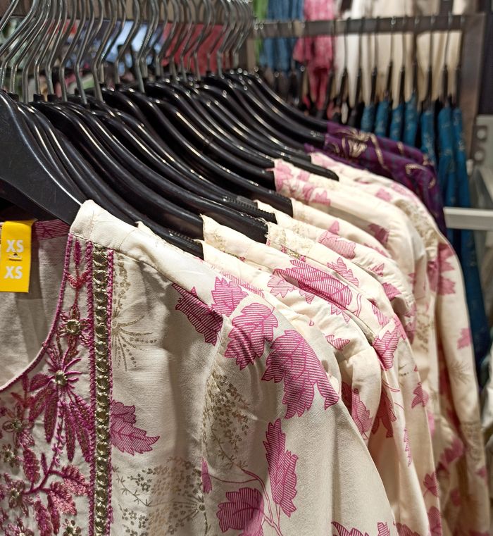 Elegant floral printed garments hung neatly on black hangers in a store.