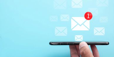 Hand holding smartphone with new email notification on screen.