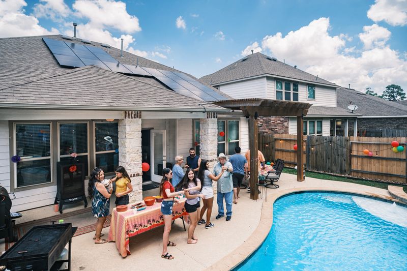 Mexican American family having a party in backyard of sustainable home with solar panels on the roof. Suburb area of Houston, Texas.