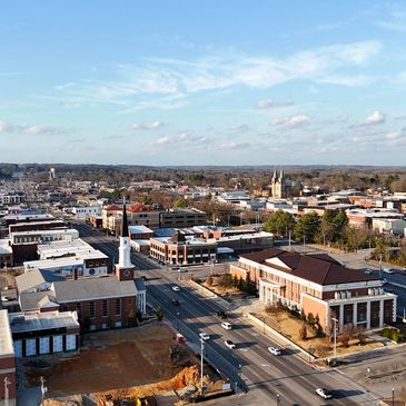 Aerial view of a small town with churches and commercial buildings under a clear blue sky.