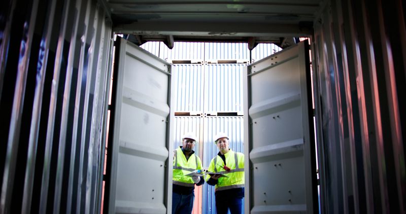 Blue collar worker works at commercial dock. Male Port Worker Opening Shipping Cargo Container to inspect the readiness of the box container