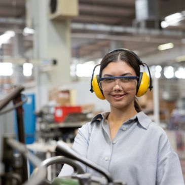 Woman wearing safety gear in a workshop.