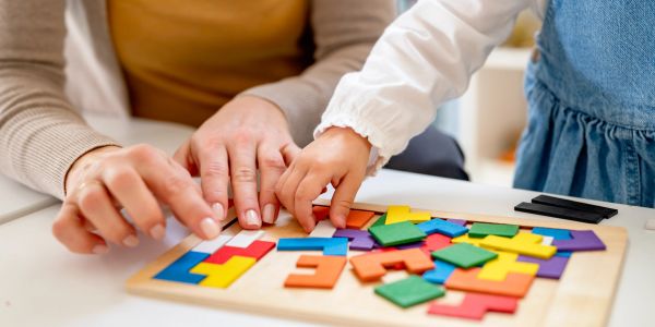 Adult and child solving a colorful wooden puzzle together.