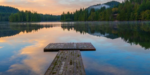 Wooden dock on a calm lake at sunset.