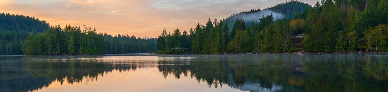 A serene landscape featuring rolling hills, a clear blue sky, and a tranquil lake reflecting the surroundings.