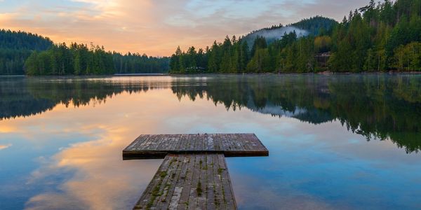 Wooden dock on a calm lake at sunset.