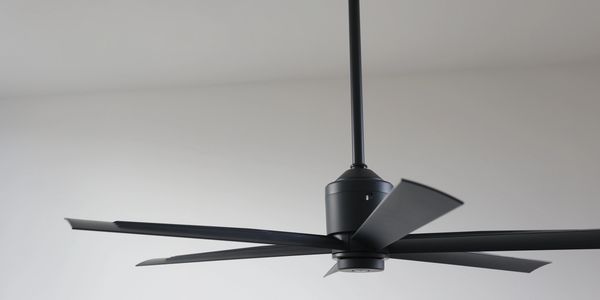 Modern black ceiling fan with six blades against a plain white ceiling.