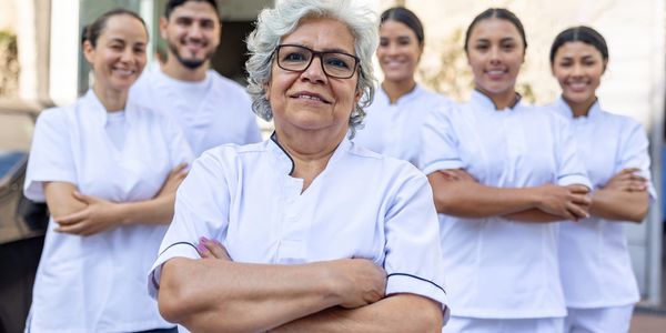 Confident senior nurse leading a diverse medical team in white uniforms.