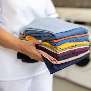 Person holding a neatly folded stack of colorful clothes.