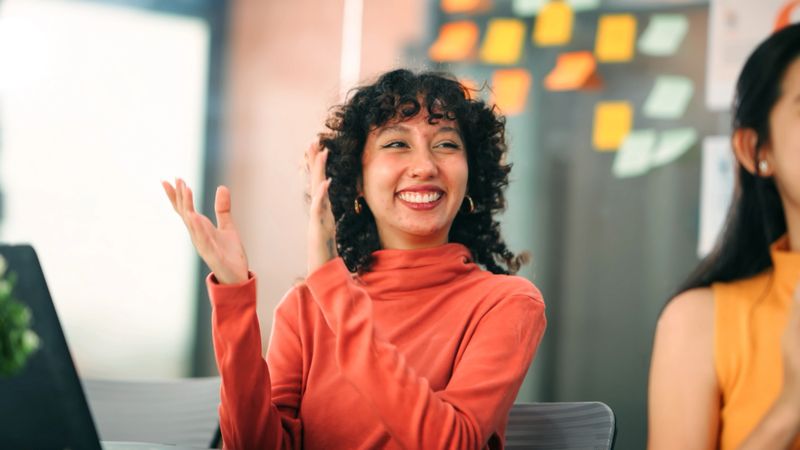 Excited woman clapping in a business event, symbolizing positivity, teamwork, and professional growth.