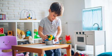 Young boy playing with toys in a bright playroom.