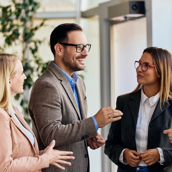 A group of professionally dressed people having a friendly conversation indoors.