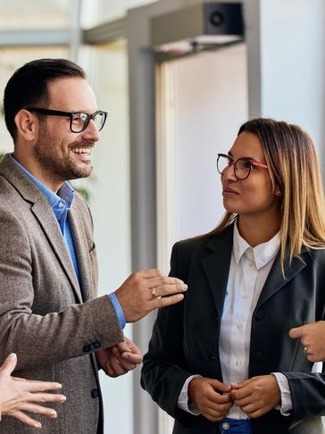 Two professionals engaged in a lively business conversation indoors.