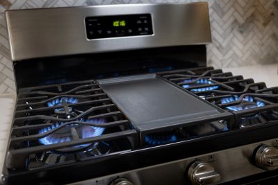 Gas stove burners lit with blue flames and a griddle.