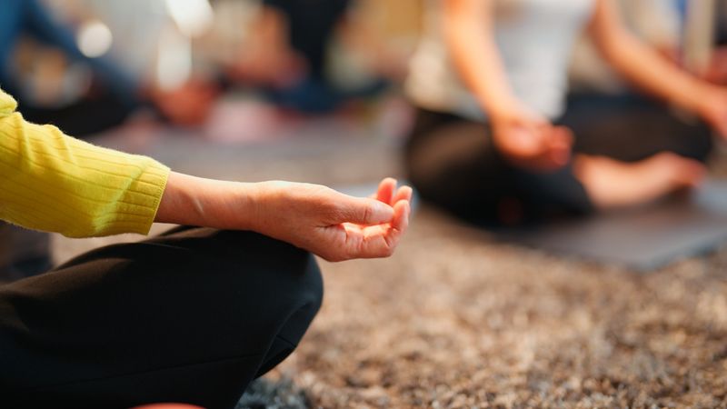 A close-up view of hands in a meditation pose during a wellness session, focusing on mindfulness and relaxation in a sustainable office environment.