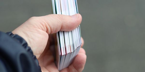 Hand holding a stack of cards with a blurred background.