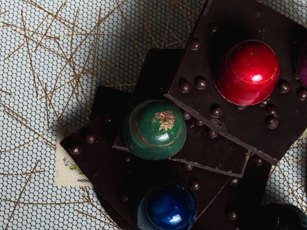 Dark chocolate squares with colorful, glossy spherical decorations.
