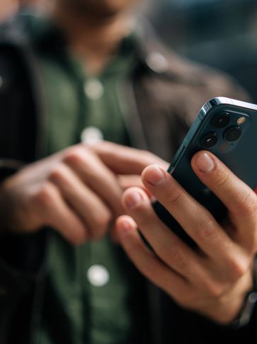 Person using a smartphone with focus on the hand and device.
