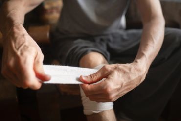 Man wrapping bandage around knee.