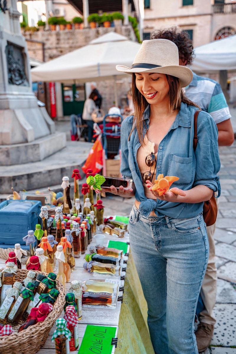 Smiling young woman explores a vibrant outdoor market in Dubrovnik, examining local products on display