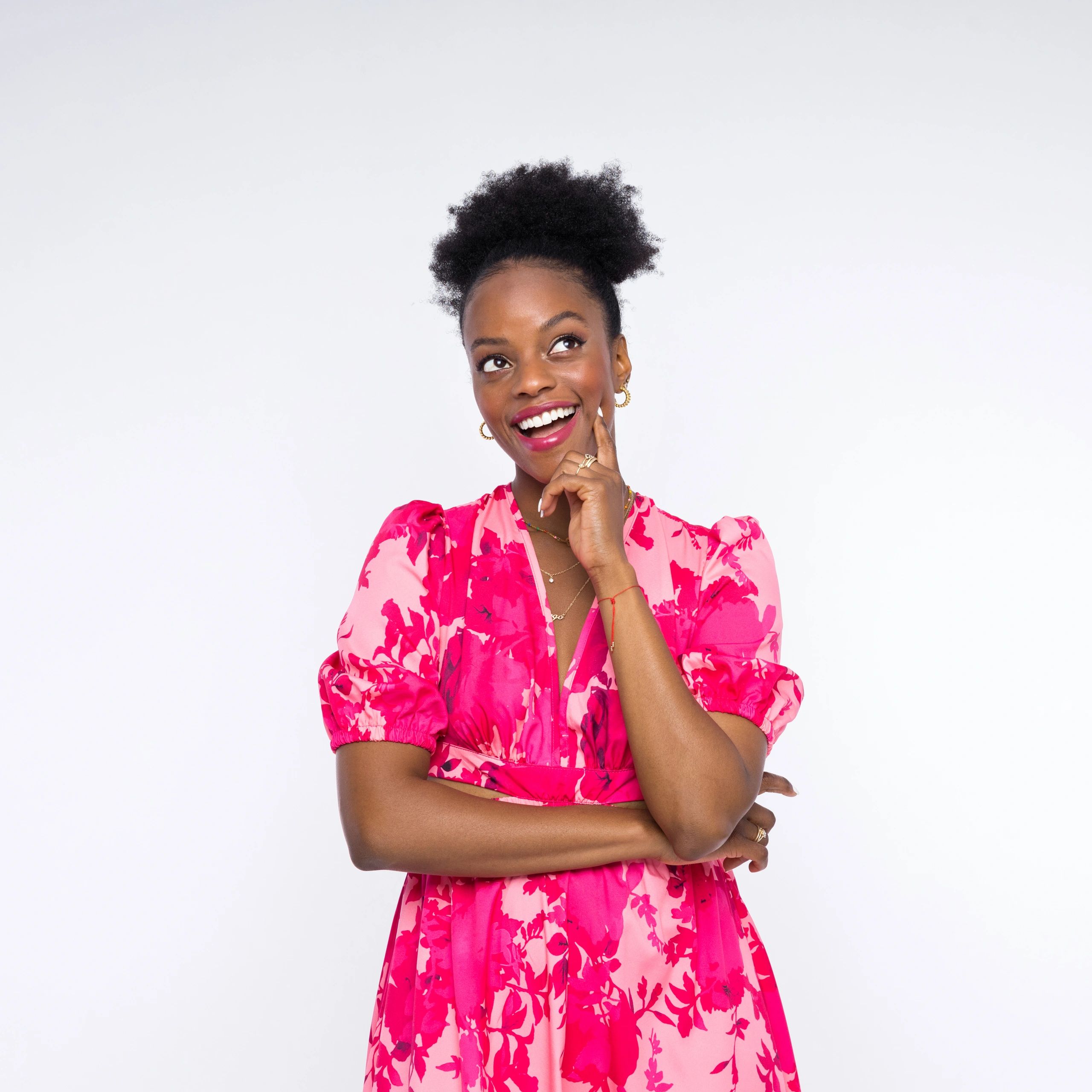 Smiling woman in a pink floral dress looking up.