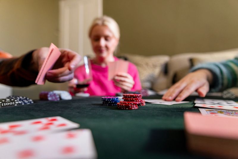 A medium shot that is focused on the poker chips central in the table. the woman in the background is out of focus looking at her cards.Videos are available similar to this scenario.