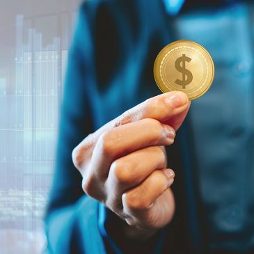 Person holding a gold coin with a dollar sign, symbolizing finance.