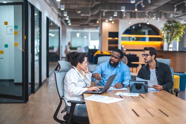 Three diverse colleagues engaged in a focused meeting in a modern office.
