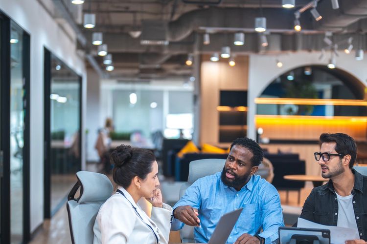 Three diverse colleagues engaged in a focused meeting in a modern office.