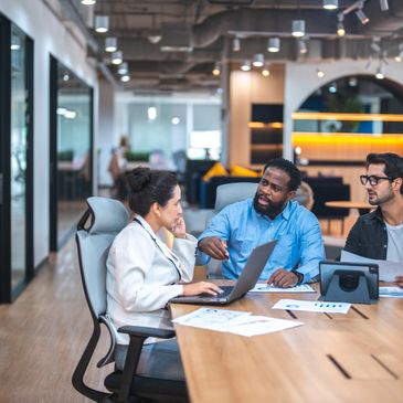 Three diverse colleagues engaged in a focused meeting in a modern office.
